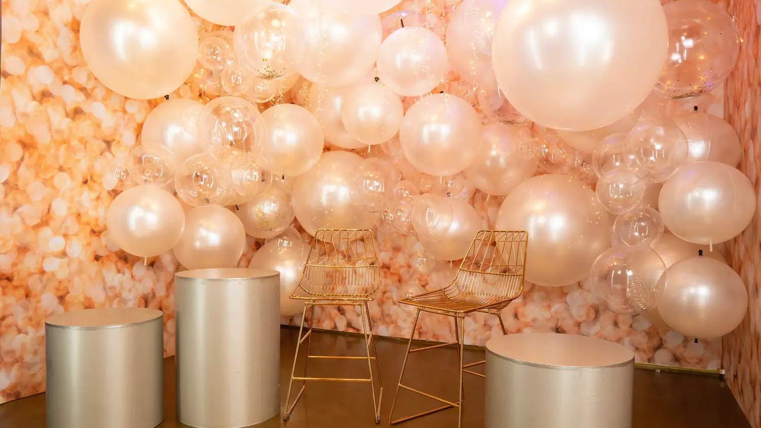 Escenario con globos en tonos marfil y sillas doradas